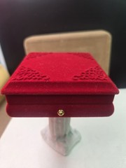 red velvet jewelry box featuring corner detailing and a gold-colored button…